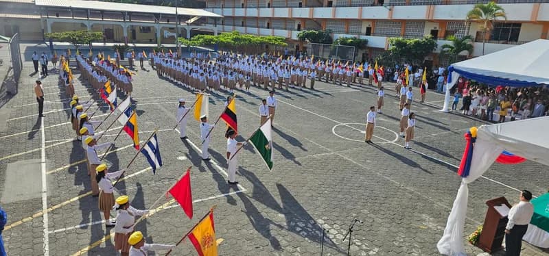 Estudiantes formados con banderas y escoltas durante un acto cívico en el patio de la institución